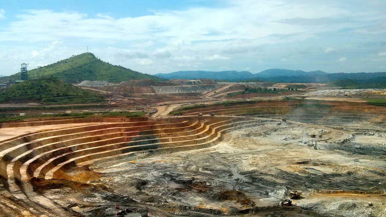 Exploitation à ciel ouvert bordée de collines boisées